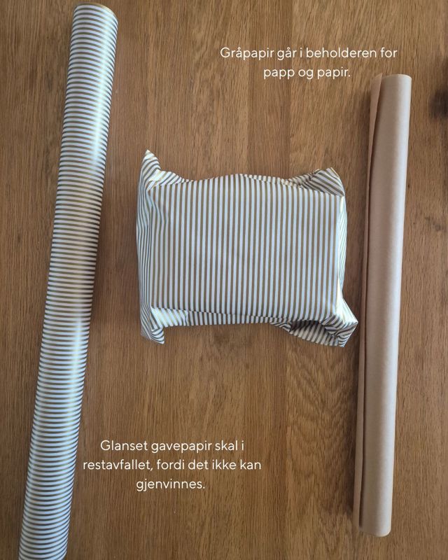 To ruller gavepapir og en innpakket gave ligger på et trebord. Den ene rullen og gaven er i glanset papir med striper, mens den andre rullen er i matt gråpapir. Teksten på bildet forklarer at glanset gavepapir skal i restavfall, mens gråpapir sorteres som papp og papir.
