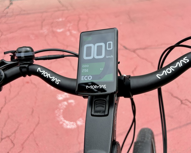 Et elsykkelstyre med skjerm som viser at det har blitt kjørt 29 mil på sykkelen. Bakgrunnen er en rød asfaltert sykkelvei.