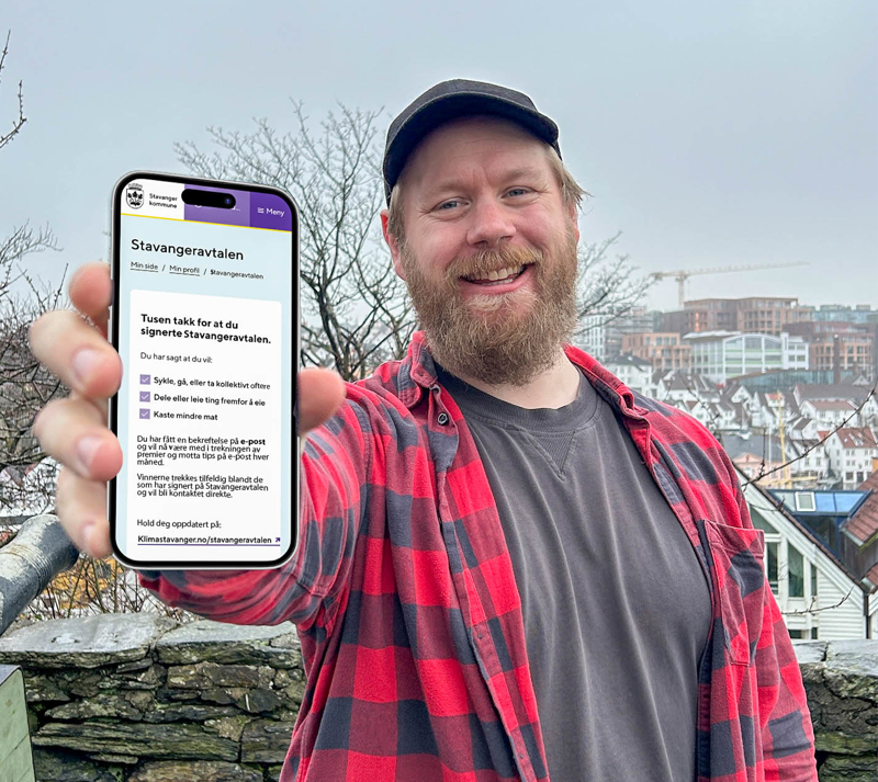 En mann holder opp en mobil hvor det står "Takk for at du signerte Stavangeravtalen"