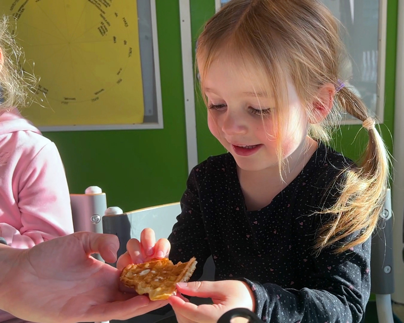 Fem år gammel jente får en vaffel. Jenta smiler