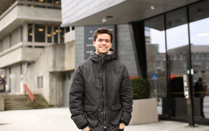 Portrettbilde av Stian. Han har mørkt, litt krøllet kort hår, skinnjakke. Han smiler.