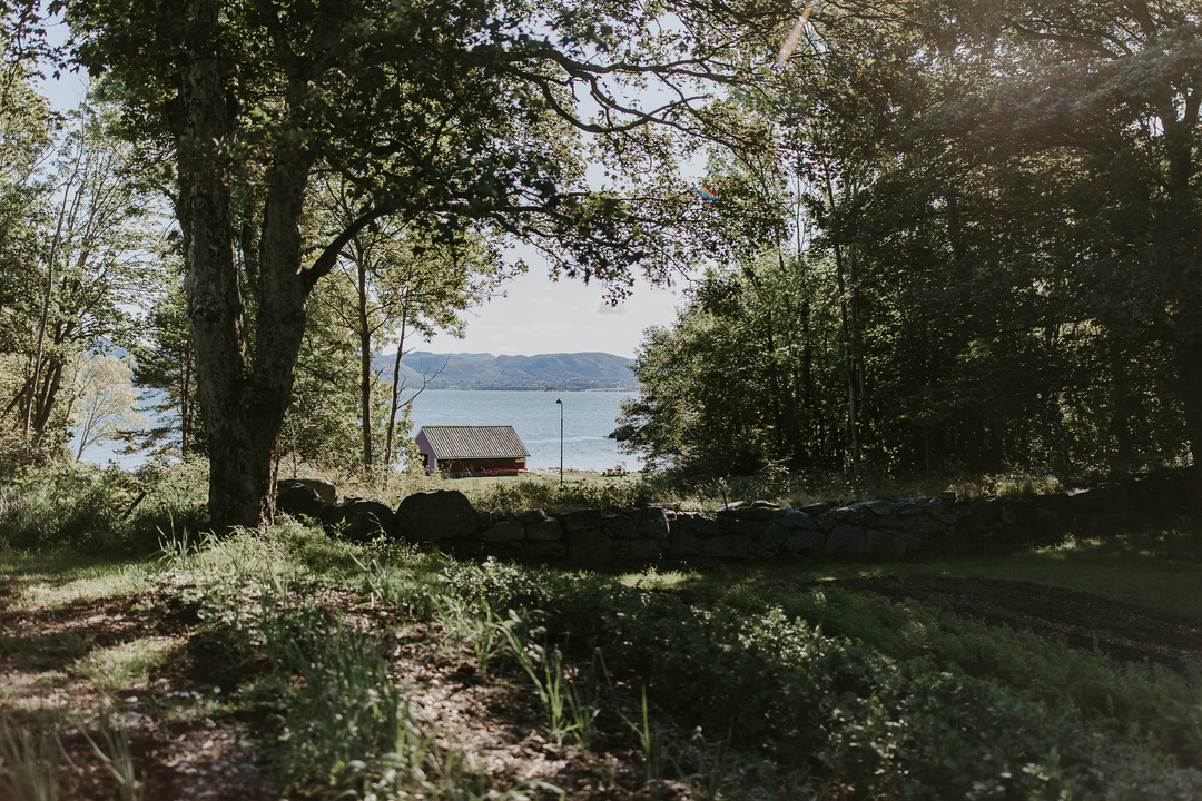 Grøntområde med et naust i bakgrunnen.