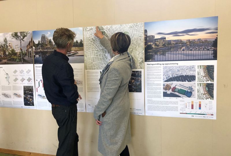 To personer som peker på plansjer med bilder av bygg.