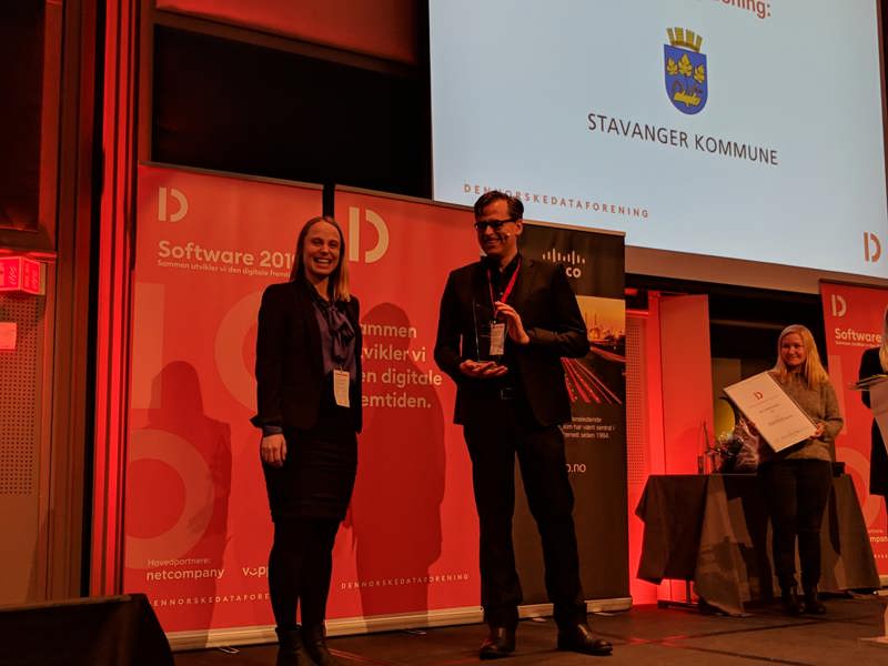 Linn S. Jensen fra kommunens smartbyavdeling mottar prisen for beste smartbyløsning 2018. Prisen deles ut av Christian Torp, generalsekretær i Den norske dataforening.  