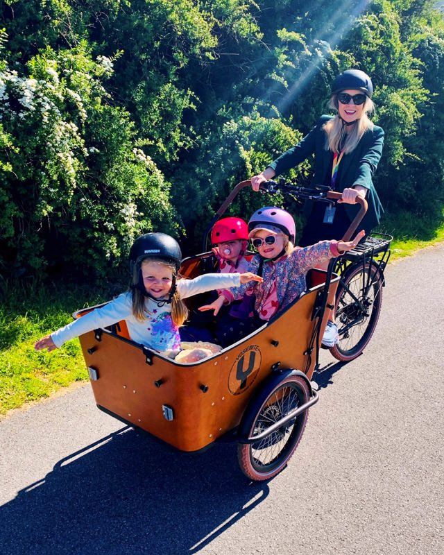 El-lastesykkel med tre barn på lasteplanet pluss syklist.