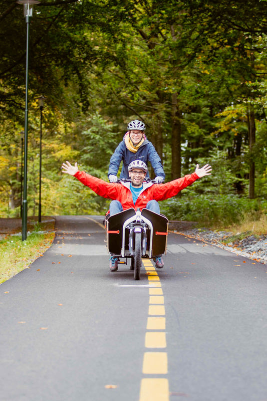 Bilde av Monica Johansen Bikos og Holger Pansch i Stavanger på sykkel i Stavanger kommune.  De sykler en lastesykkel i Vålandskogen. Foto: Andrea Ribeiro.
