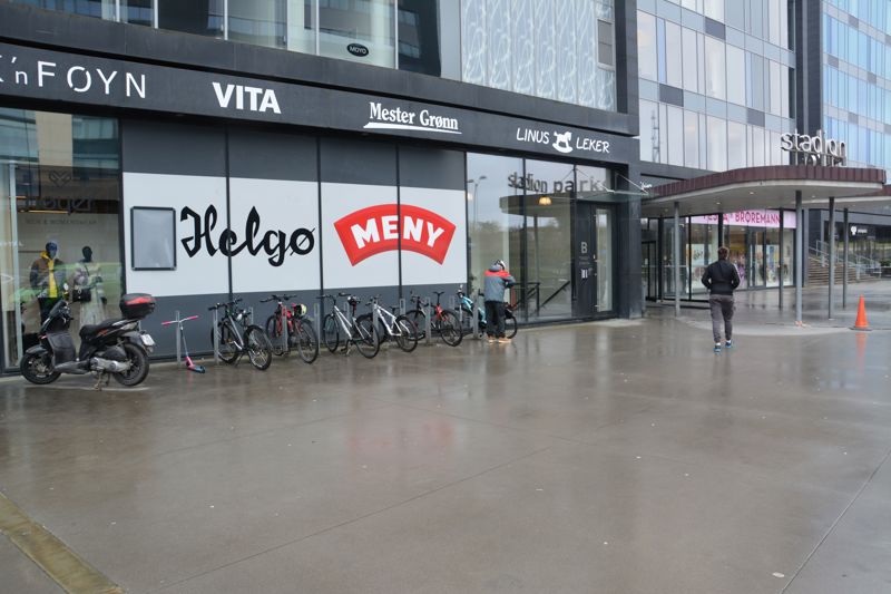 Rett ved siden av inngangen til et handlesenter er flere sykkelstativer montert.