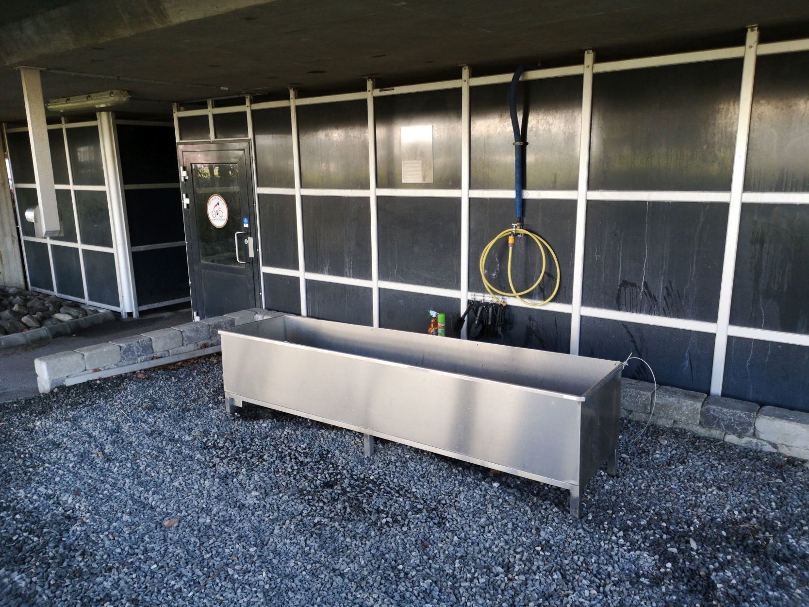 Utenfor sykkelparkeringshuset står en slags badekar der sykler kan vaskes i med en vannslange.